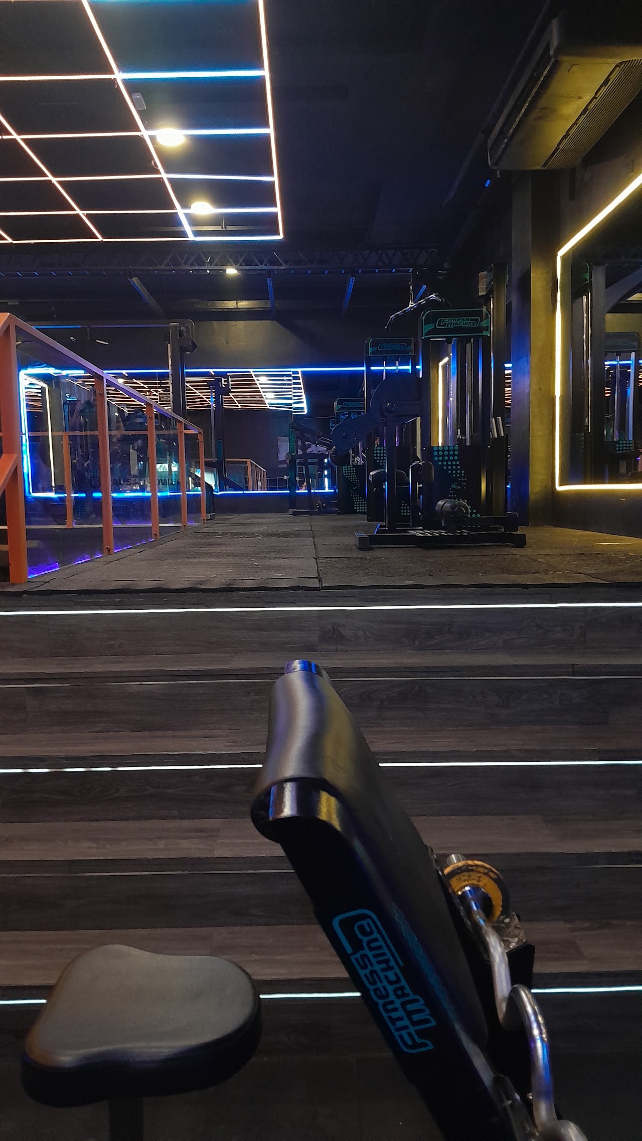 Pasillo y planta alta del gimnasio Magnus Fitness con iluminación de neón
